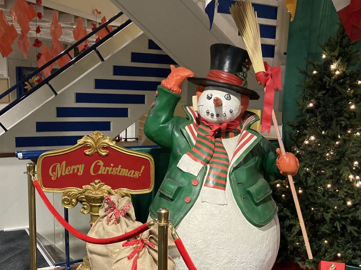 Großer Schneemann mit 'Merry Christmas'-Schild, Weihnachtsbaum und Geschenken