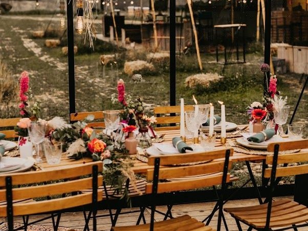 Gedeckter Hochzeitstisch mit Blumen und Kerzenlicht unter einem Glaszelt