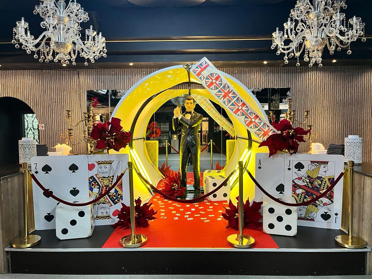 Casino-Themenparty mit James-Bond-Figur, Kartendekor, Würfeln und rotem Teppich