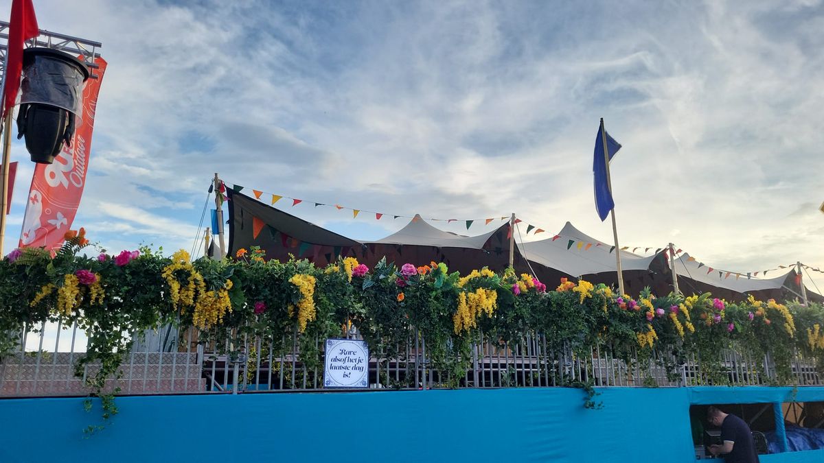 Festivaldekoration mit Blumenkränzen entlang eines Zauns, Stretchzelt und Wimpeln