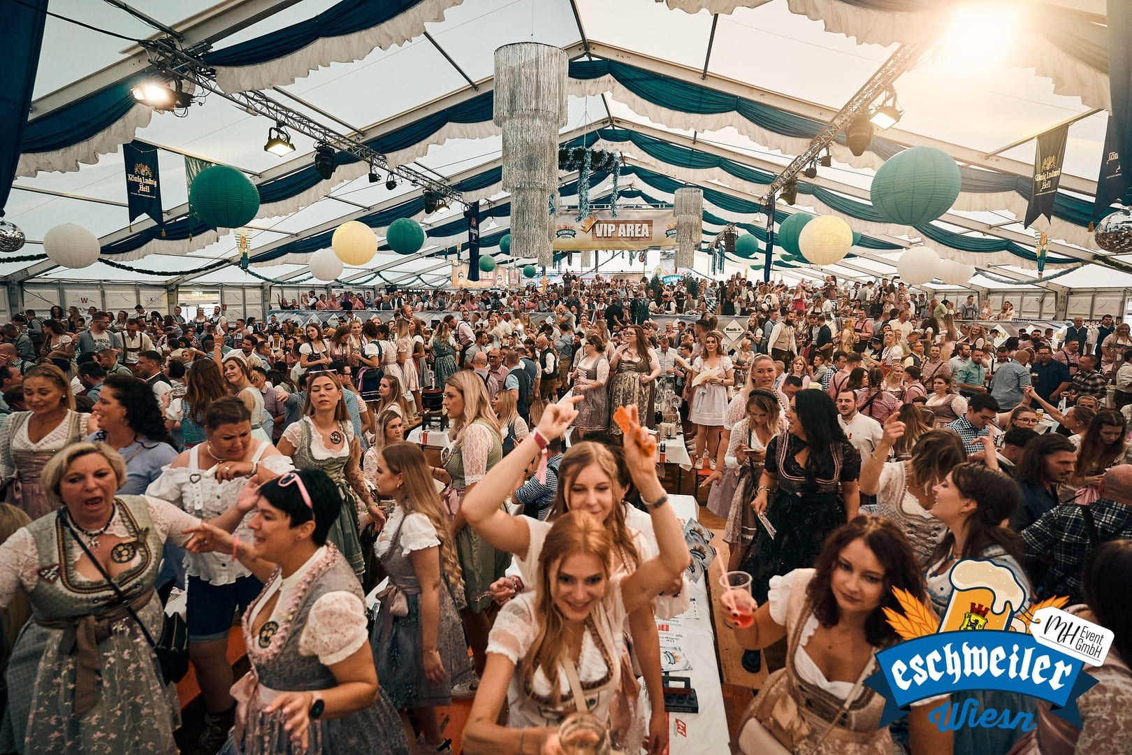 Oktoberfest-Saal mit Biertischen, blau-weißer Dekoration und bayerischen Fahnen