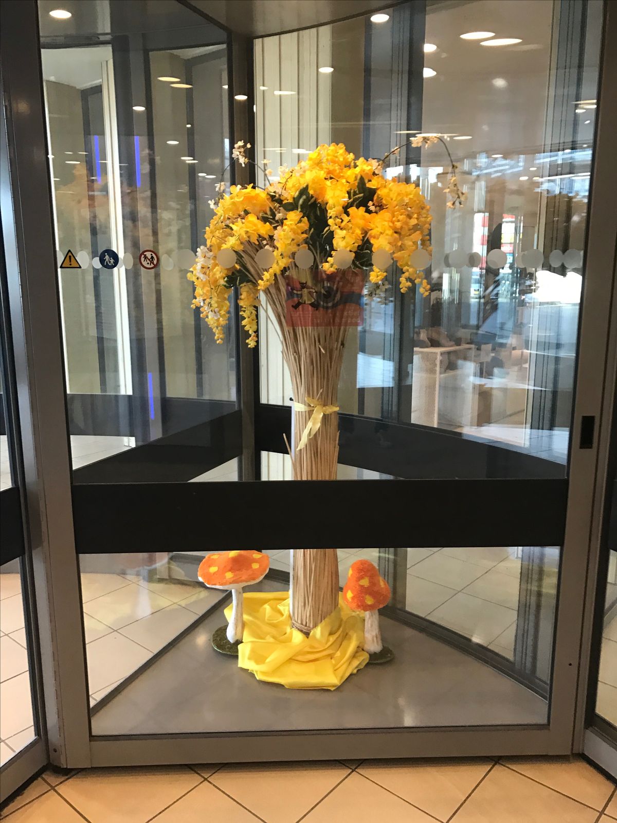 Blumendekoration mit gelben Orchideen in den Drehtüren eines Einkaufszentrums